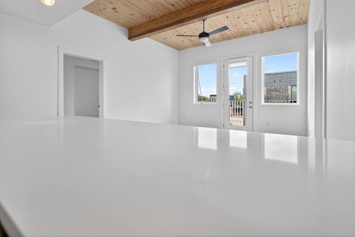 A white room with a ceiling fan and three windows.