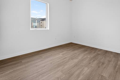 A room with a window and wooden flooring.