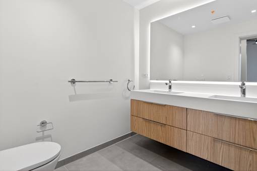 A white toilet sits next to a white sink in a modern bathroom.