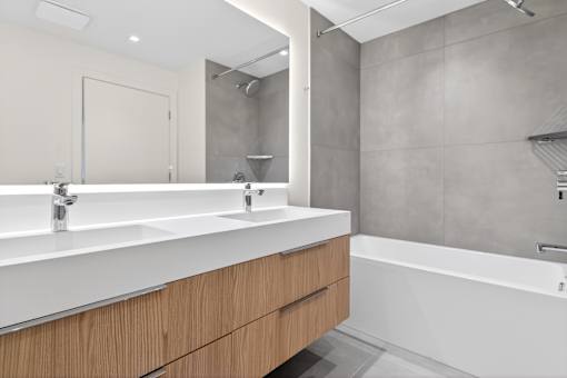 A modern bathroom with a white sink and wooden drawers.