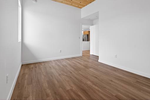 A room with wooden flooring and white walls.