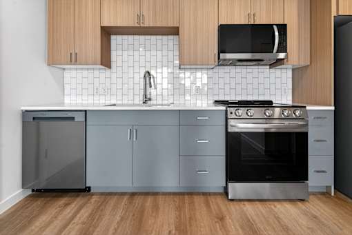 A modern kitchen with a stainless steel refrigerator, oven, and cabinets.