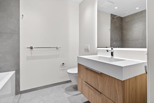 A modern bathroom with a toilet, sink, and bathtub.