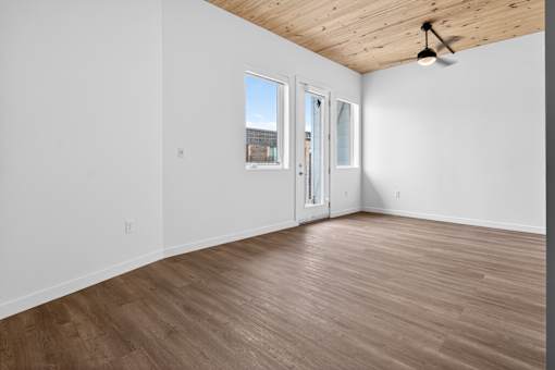 A room with a ceiling fan and a view of a building outside the window.