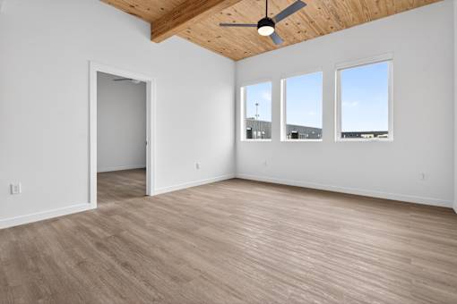 A room with a ceiling fan and three windows.