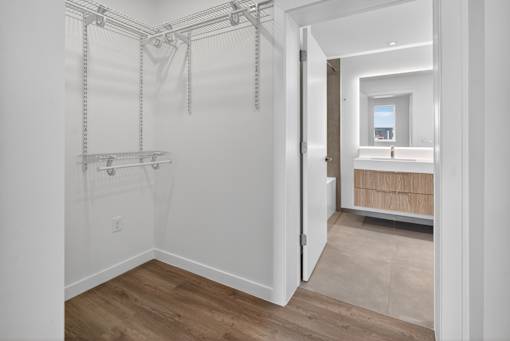 A white bathroom with a walk-in shower and a doorway leading to a bedroom.