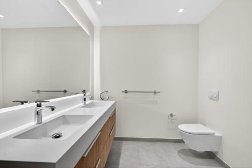 A white toilet sits next to a white sink in a bathroom.