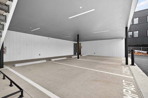 A parking garage with a white ceiling and concrete floor.