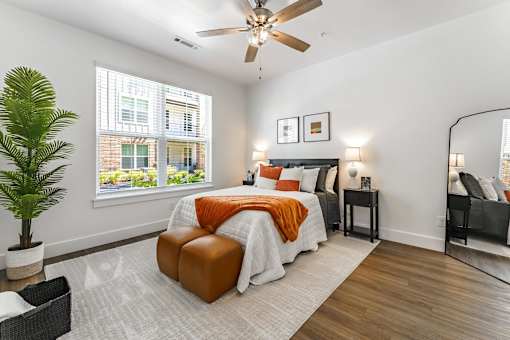 A bedroom with a bed, a chair, and a plant.