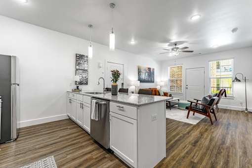 A modern kitchen with white cabinets and a wooden floor.