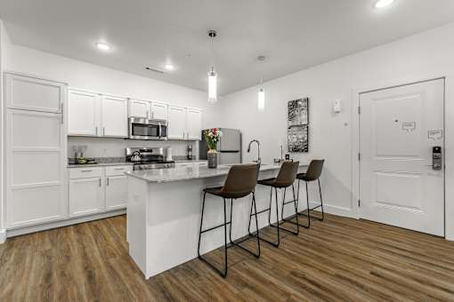A kitchen with white cabinets and a wooden floor.