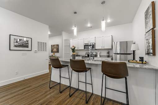 A kitchen with white cabinets and brown barstools.