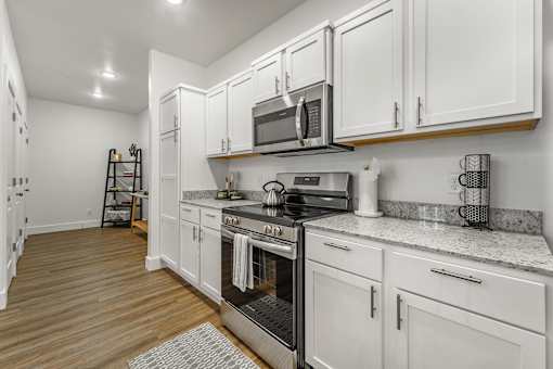 A kitchen with white cabinets and a black stove top oven.