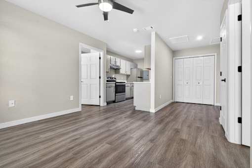 A spacious kitchen and living room with wood flooring and white walls.