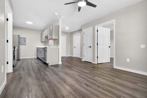 A spacious kitchen with a ceiling fan and wooden flooring.