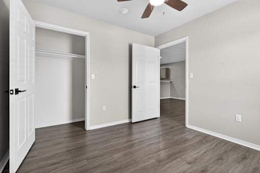 A room with a ceiling fan and three doors.