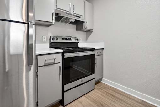 A modern kitchen with a stainless steel refrigerator and an oven with a stove on top.