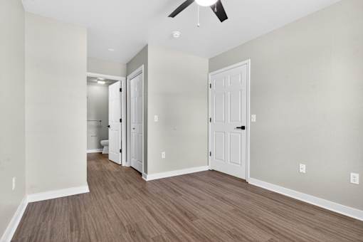 A room with a white door and a ceiling fan.