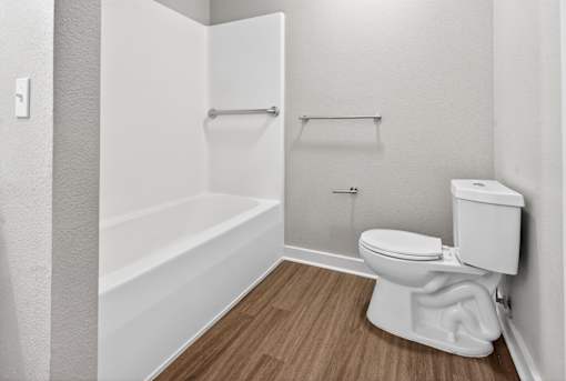 A white toilet in a small bathroom with a white bathtub.