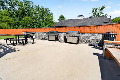 A patio with a table and chairs is surrounded by a stone wall.