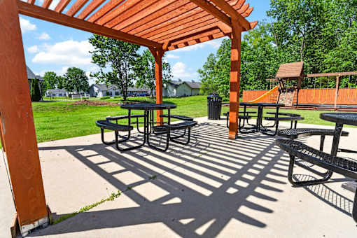 A picnic area with tables and benches under a wooden pergola.