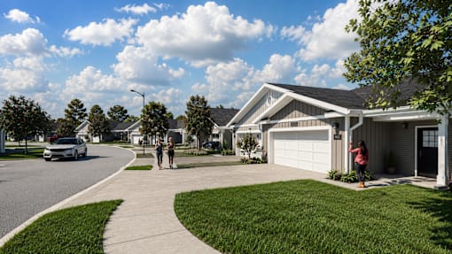 Two people are walking on a sidewalk in front of a house.