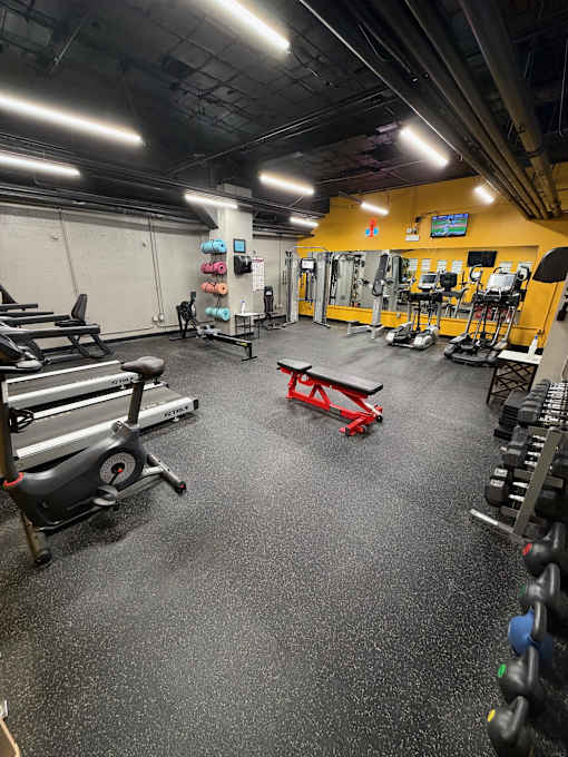 A gym with a variety of equipment including weights and a treadmill.