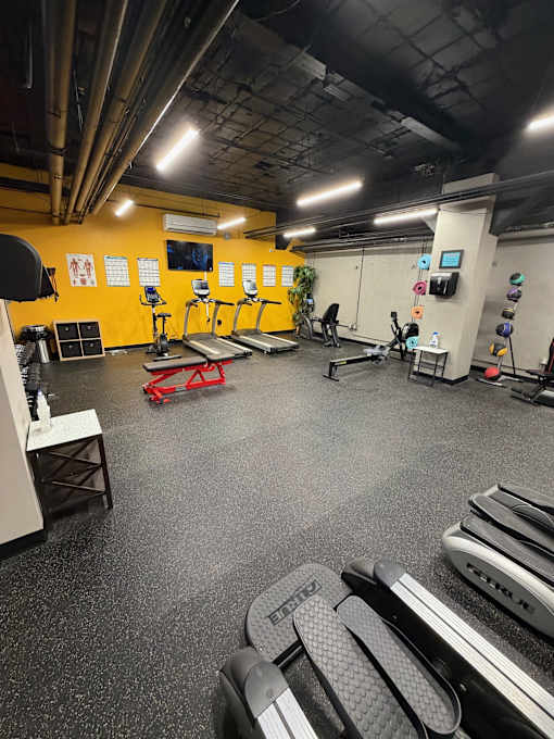 A gym with a variety of equipment including treadmills, weight machines, and exercise benches.