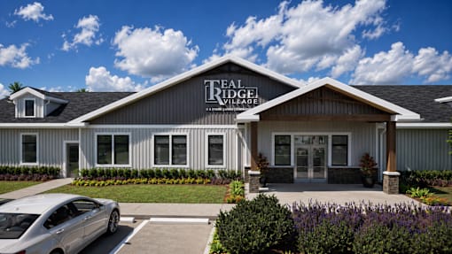 A silver car is parked in front of a building with a sign that says "The Ridge Village".