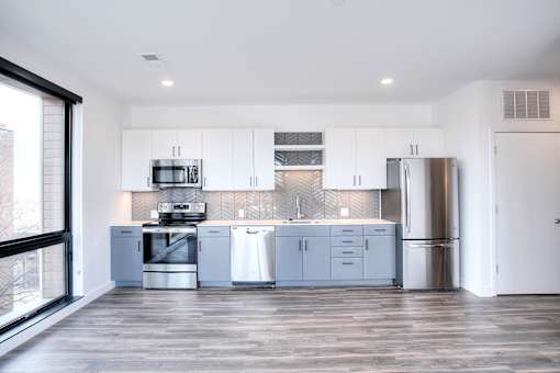 A modern kitchen with stainless steel appliances and wooden flooring.