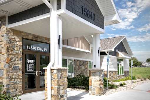The image shows a building with a stone facade and a glass door with a sign that reads "15840 Clay Rd."