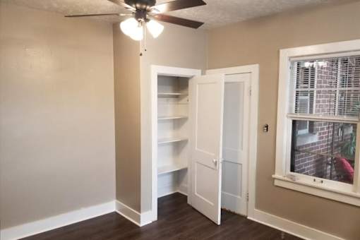 A room with a ceiling fan and a window with blinds.