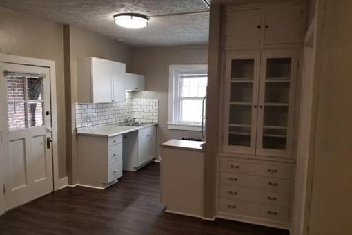 A kitchen with white cabinets and a window.
