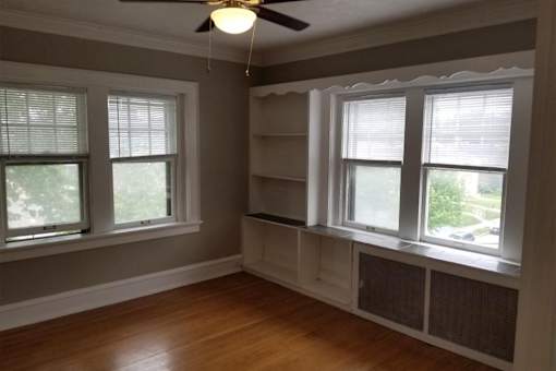 A room with a window and a fan on the ceiling.