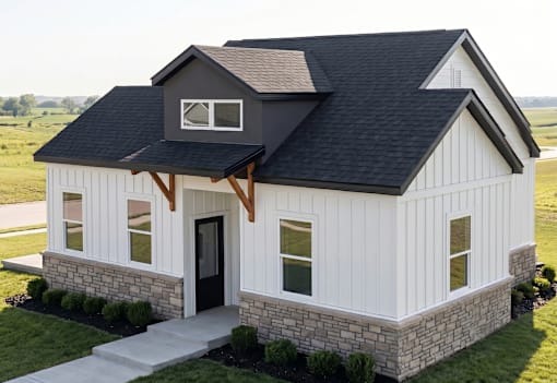 A white house with a black roof and a stone foundation.