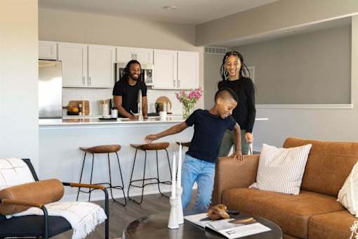 A family of three is standing in a modern kitchen.