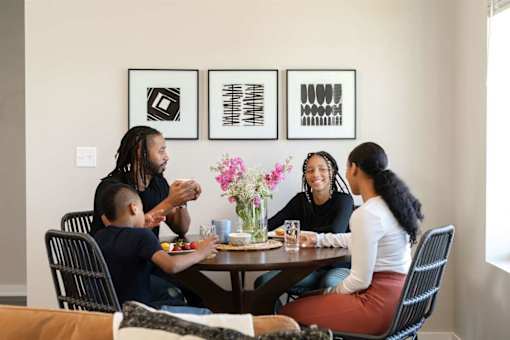 A family of four is sitting around a table eating.