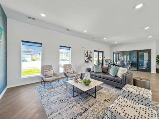 A living room with a grey sofa, a coffee table, and two chairs.