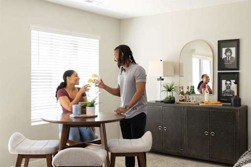 A man with dreadlocks is serving a woman a drink at a table.