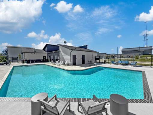 A swimming pool surrounded by lounge chairs and a building in the background.