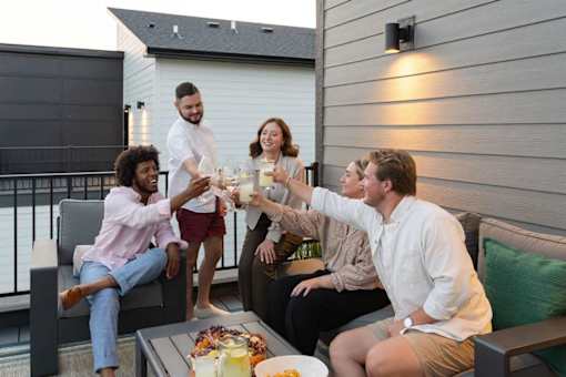 A group of people toasting with drinks on a balcony.