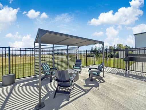 A patio with a black fence, a grey table and chairs, and a white canopy.
