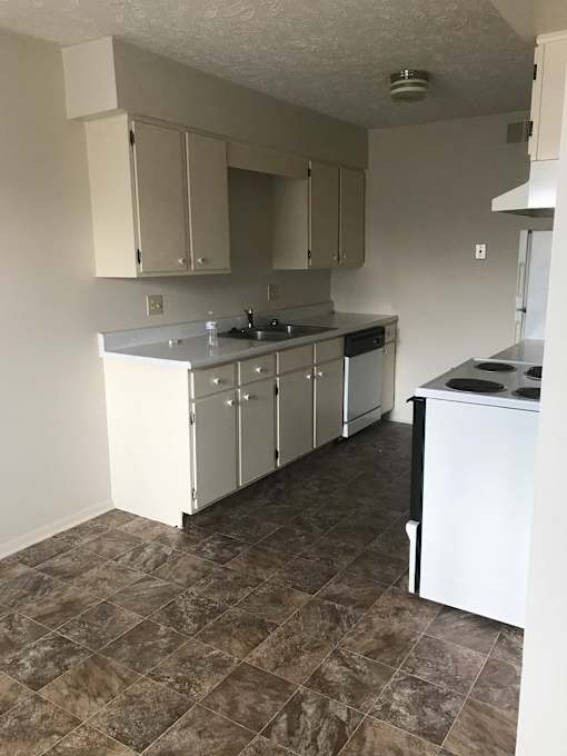 A kitchen with white cabinets and a tiled floor.