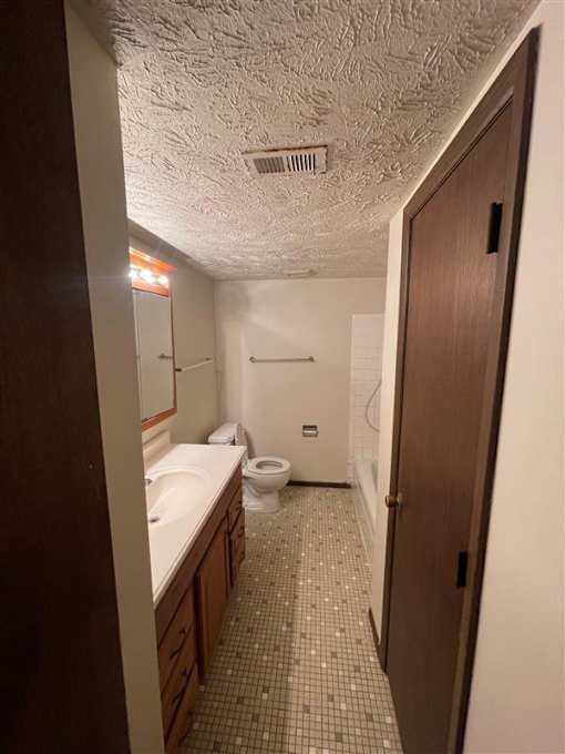 A bathroom with a toilet, sink, and mirror.