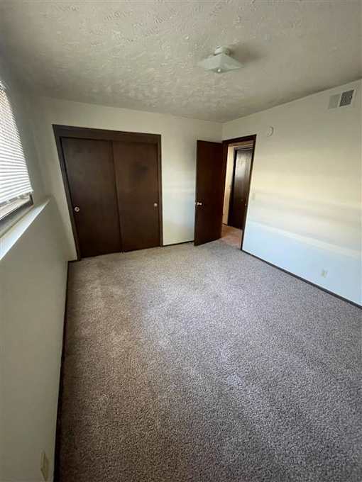 A room with carpeted floor and two doors.