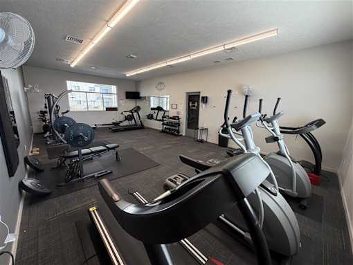 A gym with a variety of exercise equipment including treadmills, stationary bikes, and weight machines.