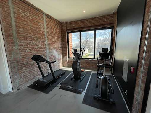 A room with a brick wall and a treadmill.