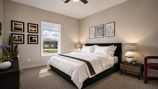 A bedroom with a large bed, a ceiling fan, and pictures on the wall.