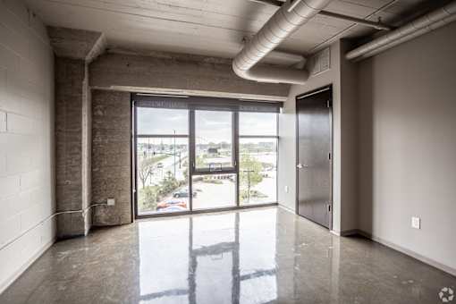 A large empty room with a view of the outside through the glass doors.