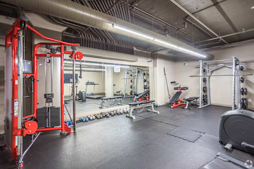 A gym with a red weight machine and various other equipment.